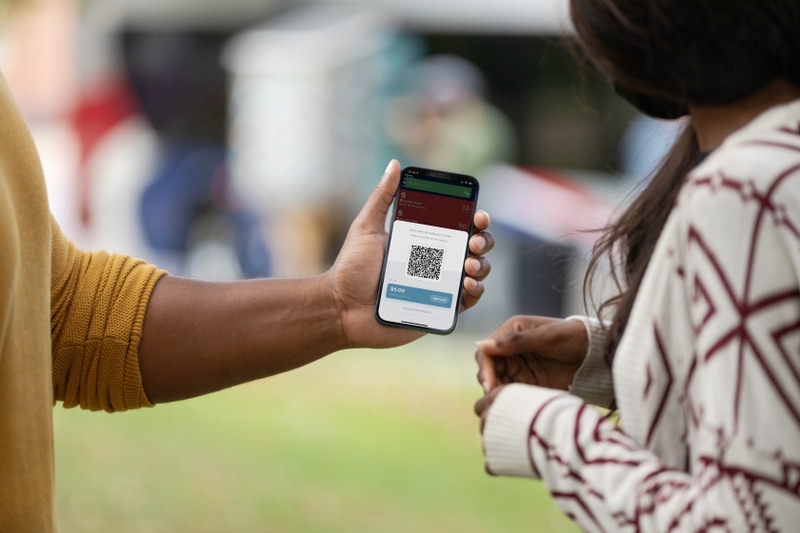 Man showing mobile ticketing app on phone to another person